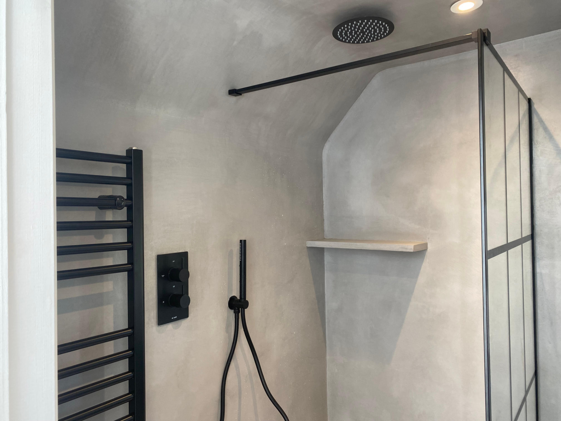 Microcement wet room with concealed shower valve and black towel rail