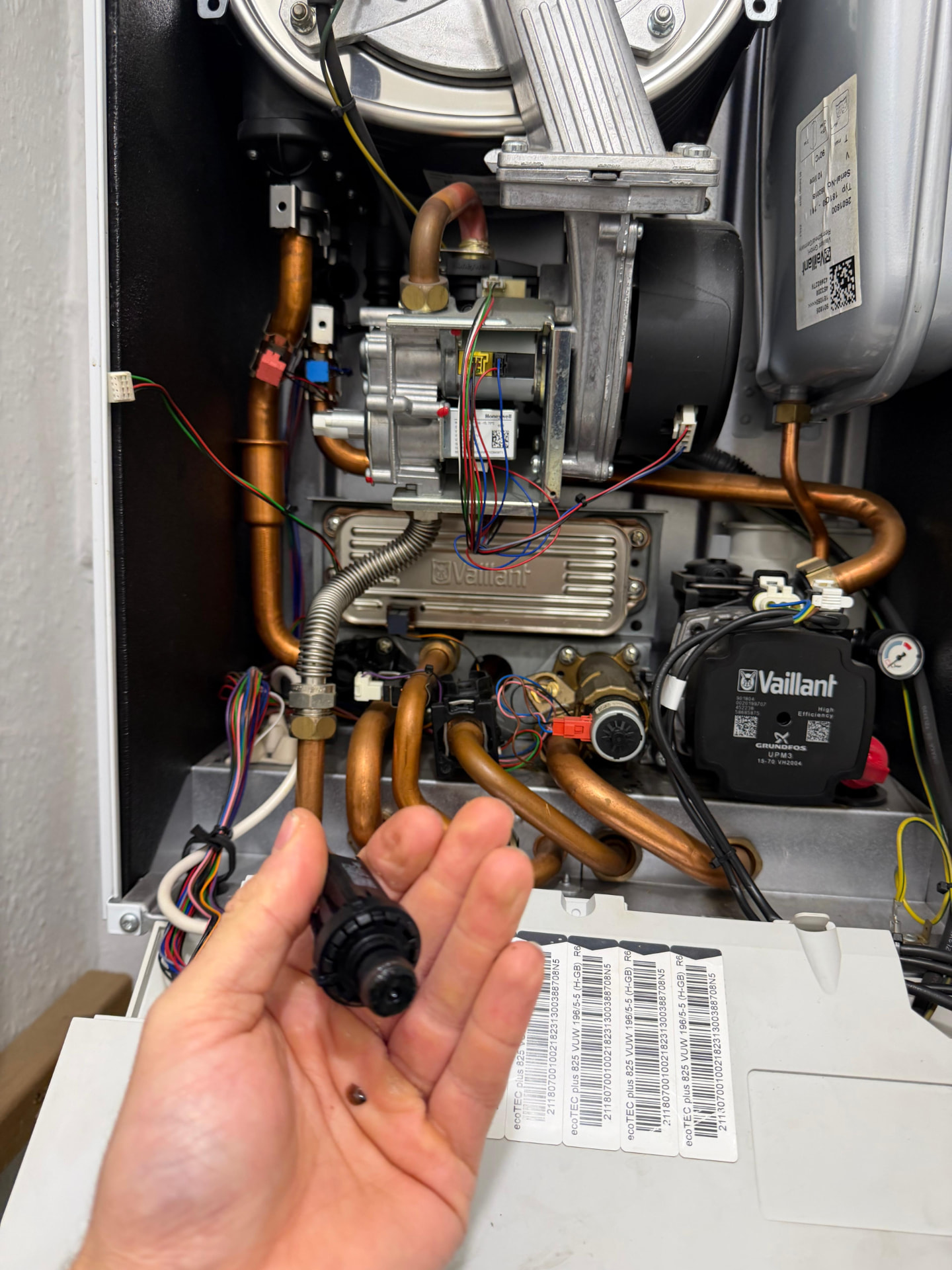 Engineer replacing a component inside an open Vaillant ecoTEC boiler